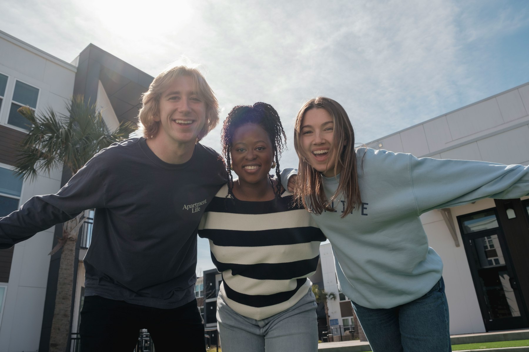 Three friends smiling with their arms around each other